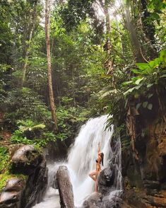 a woman standing in the middle of a waterfall