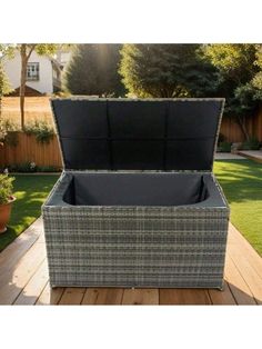 an outdoor wicker storage box on a deck with grass and trees in the background