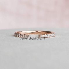 a rose gold wedding band with five diamonds on the top and bottom, sitting on a white surface