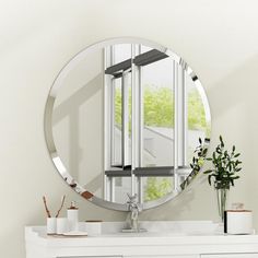 a bathroom with a round mirror on the wall and a white dresser in front of it