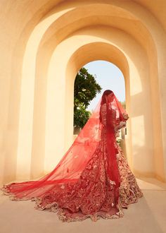 a woman in a red bridal gown standing under an archway