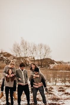 a group of young people standing in the snow with their arms around each other and looking at the camera