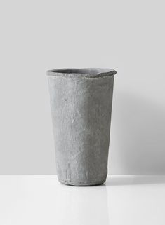 a grey pot sitting on top of a white table next to a gray wall and floor