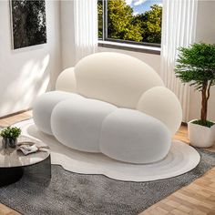 a modern living room with white furniture and plants in the window sill, along with a round coffee table