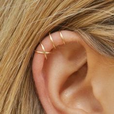 a woman's ear is shown with two small gold rings on top of it