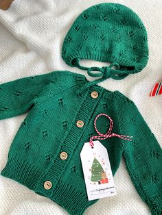 a green knitted sweater with a christmas tree on the front and a tag attached to it