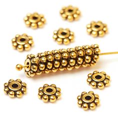 gold plated metal beads with black stones on them, set against a white background