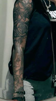 a man with tattoos on his arm holding a cell phone