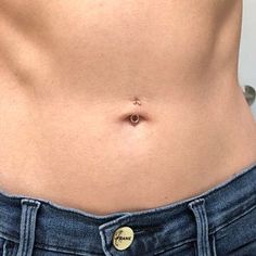 a woman's stomach showing her tiny belly ring and the bottom part of her jeans