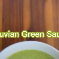 a white bowl filled with green soup on top of a wooden table