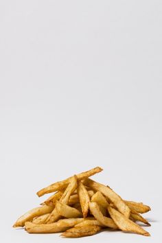 french fries are piled up on a white surface