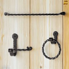 two black handles on a wooden door with rope hanging from it's handlebars