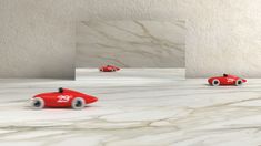 three red toy cars sitting on top of a white marble floor next to each other