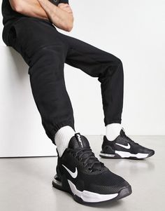 a man in black pants and sneakers sitting on a wall