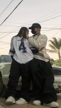 two people standing next to each other in front of a car