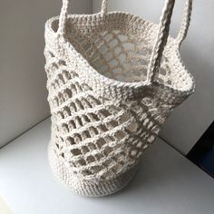 a white crocheted bag sitting on top of a table next to a wall