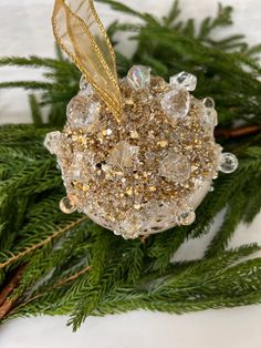 a glass ornament with gold glitter and a feather on it's back