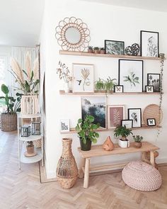 a living room filled with lots of plants and pictures on the wall next to a wooden table