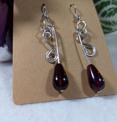 pair of earrings with red glass tears sitting on top of a piece of paper