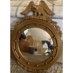 a mirror with an eagle on it is sitting on the floor in front of a bed