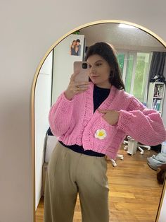 a woman taking a selfie in front of a mirror wearing a pink sweater and khaki pants