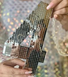 a woman is holding up a piece of mirrored paper that has been cut into triangles