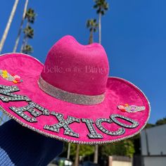 "Hat color: fuchsia pink  Hat material: suede Hat size: M or L -Beautifully adorned with crystal AB rhinestones on the bottom brim -The back part of the hat says \"MEXICO\" and has 2 sugar skulls with flowers perfect for representing at any Mexican celebration such as cinco de mayo, dia de los muertos, and more! Stand out and sparkle in style <3 Follow me on Instagram: @BelleoftheBlingco for more inspo!" Pink Wide Brim Mini Hats For Rodeo, Pink Wide Brim Costume Hat For Festival, Adjustable Western Hat For Cinco De Mayo, Pink Mini Hat For Festivals, Pink Wide Brim Mini Hat For Festival, Pink Curved Brim Hat Personalized, Pink Western Mini Hat For Rodeo, Pink Mini Hat For Summer Rodeo, Western Pink Costume Hats And Headpieces For Rodeo