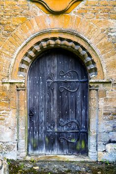 an old wooden door with iron bars on the front and side of a brick building