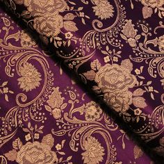 purple and gold brocaded fabric with floral designs on it's edges, close up