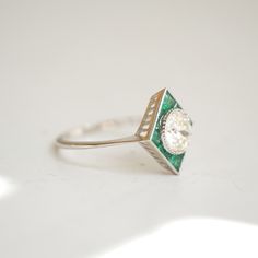 Item Details: One natural old European cut center diamond weighing approx. 0.80 ctw, H color VS clarity. Natural calibre cut emeralds, approx. 0.46 ctw. The band is 1.25mm wide. Set in 14K white gold. This ring is created with one-of-a-kind gemstones. This item ships within 2-3 business days from the time of order. B0046 Art Deco Emerald Ring In Platinum, Art Deco Diamond Ring With Gemstone, Art Deco Platinum Emerald Ring, Art Deco Oval Emerald Ring With Brilliant Cut, White Gold Oval Emerald Ring Art Deco Style, Diamond White Emerald Ring In Platinum, Art Deco Emerald Ring With Platinum, Marquise Brilliant Cut Emerald Ring, Marquise Emerald Ring With Brilliant Cut