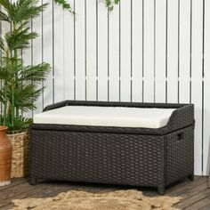 a wicker bench sitting on top of a wooden floor next to a potted plant