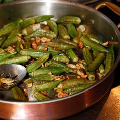 green beans and nuts are being cooked in a pan on the stove with a spoon