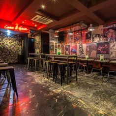 an empty restaurant with lots of tables and chairs in front of a wall full of posters