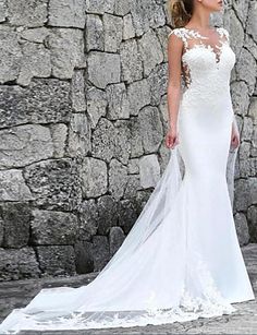 a woman in a wedding dress standing next to a stone wall