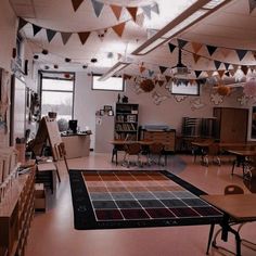 an empty room with many tables and chairs, hanging decorations on the ceiling and several bookshelves