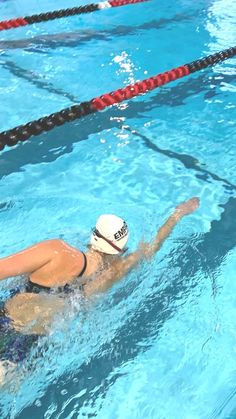 a woman swimming in a pool wearing a white hat