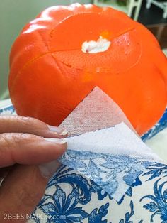 someone is peeling an orange on top of a blue and white plate with napkins