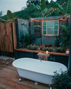 a bath tub sitting on top of a wooden floor next to a lush green wall