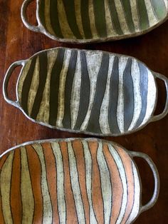 three brown and black striped dishes sitting on top of a wooden table