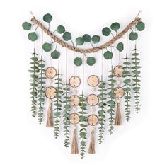 a wall hanging made out of wood and green leaves with wooden discs attached to it