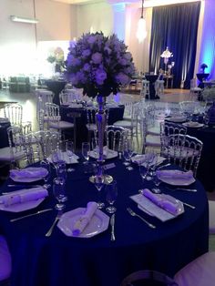 a table set up with purple flowers and place settings for an event or wedding reception