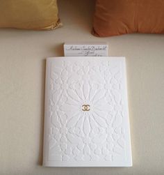 a white card with a gold ring on it sitting next to pillows and pillow cases