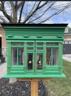 a green book store sitting on top of a wooden pole in front of a tree