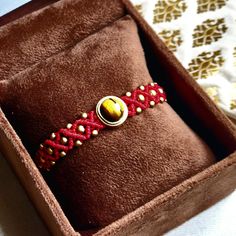 a brown box with a red ribbon and an orange beaded ring in it's center