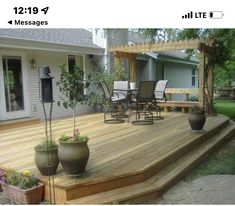 a wooden deck with chairs and potted plants on the bottom level next to it