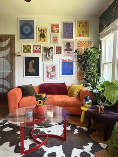 a living room filled with furniture and lots of pictures on the wall above it's glass coffee table