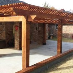 a large wooden pergoline sitting on top of a cement patio next to a brick building