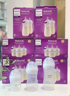 six bottles of natural breast milk sitting on a table next to each other in front of boxes