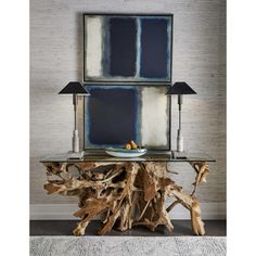 a table made out of driftwood with two lamps on top and an art piece above it