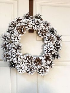 a wreath made out of pine cones hanging on a door